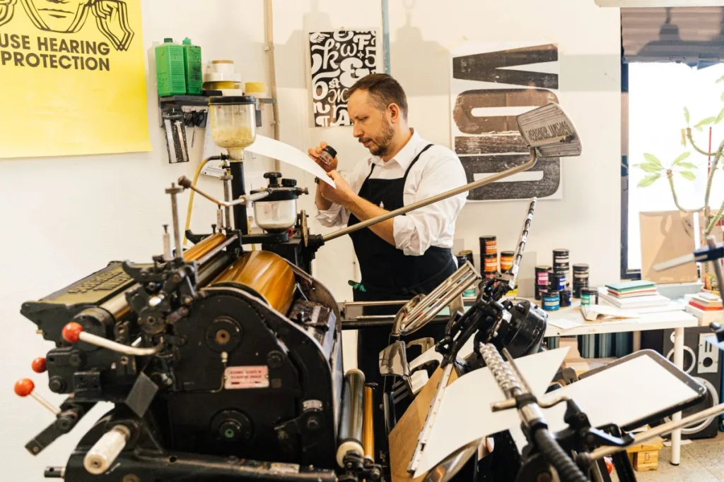 A maker working at a press in a workshop, the kind of setup a heat press sits in